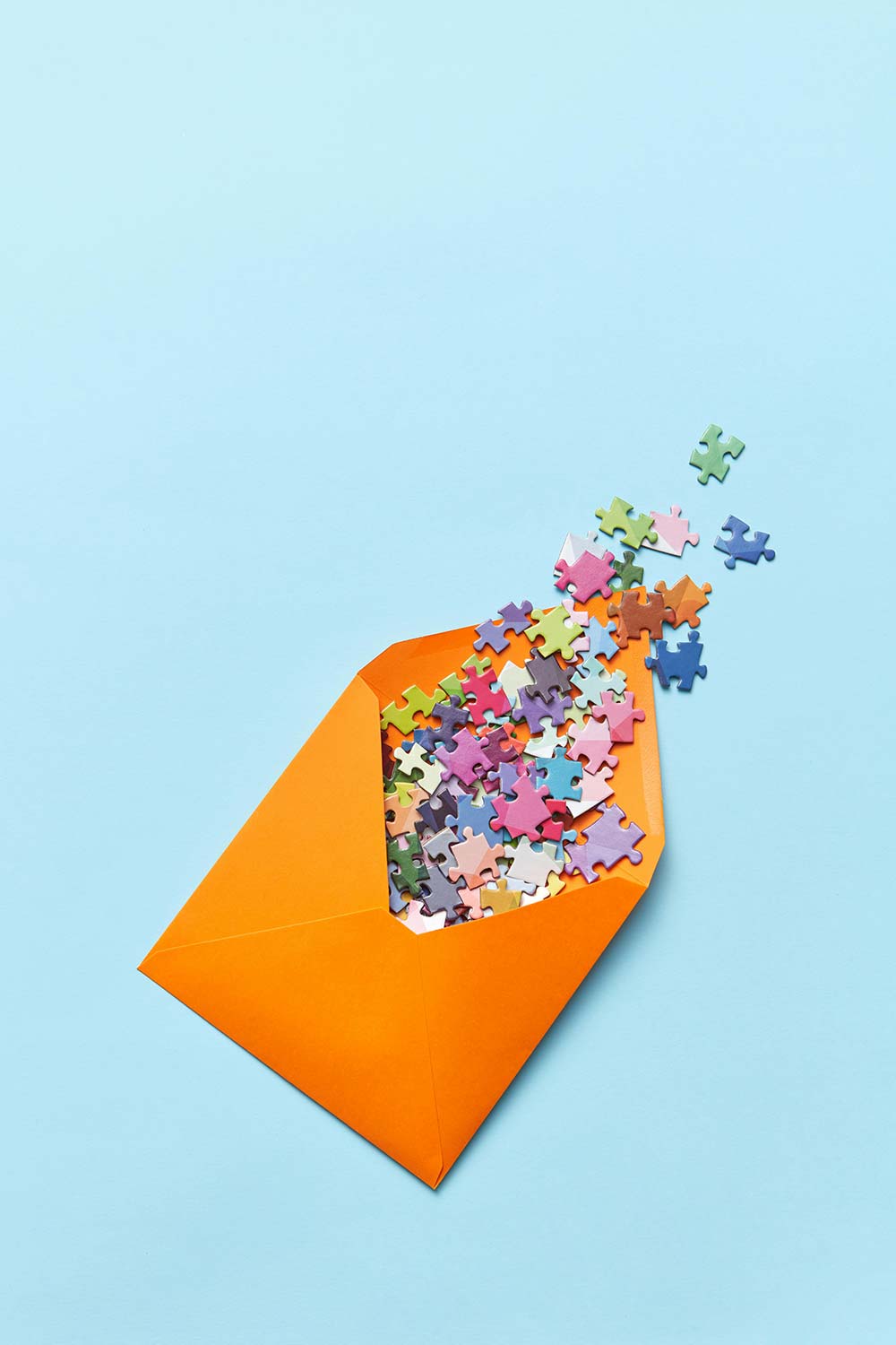 Orange envelope spilling colorful puzzle pieces for Life In UK Help newsletter.